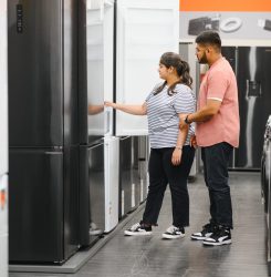 Young indian couple, satisfied customers choosing fridges in appliances store Young indian couple, satisfied customers choosing fridges in appliances store.